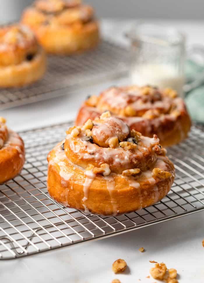 Homemade Cinnamon Rolls on a wire rack drizzled with icing