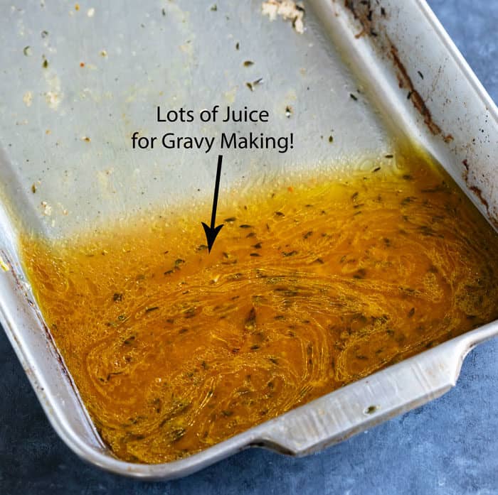 A roasted pan tiled up with juices from the cooked chicken in it for making gravy.