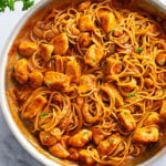 Chicken Scallopini in a skillet with a red wine reduction sauce and pasta.