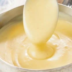 A spoon scooping up cream of chicken soup from a soup pot.