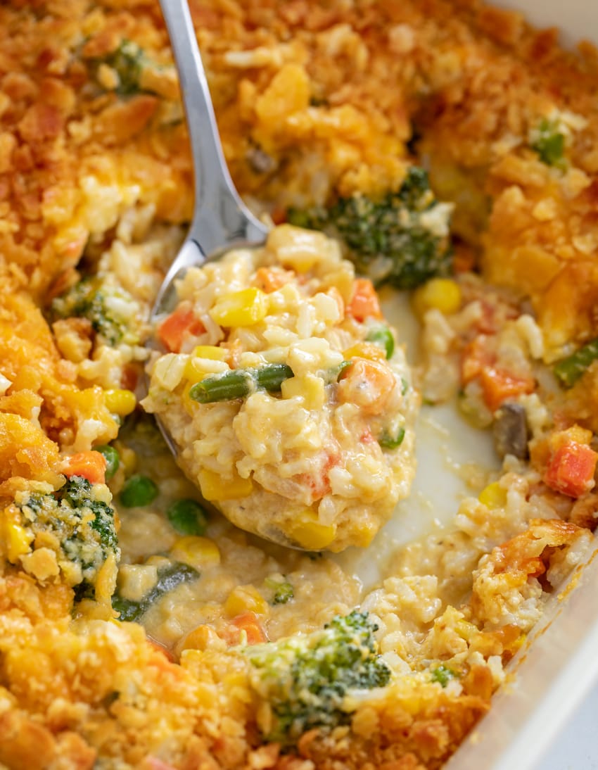 Creamy Vegetable Casserole being scooped up from a casserole dish on a spoon.