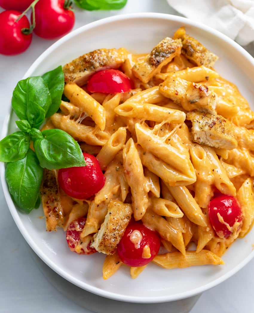 Caprese Pasta with fresh tomatoes and basil on a white plate.