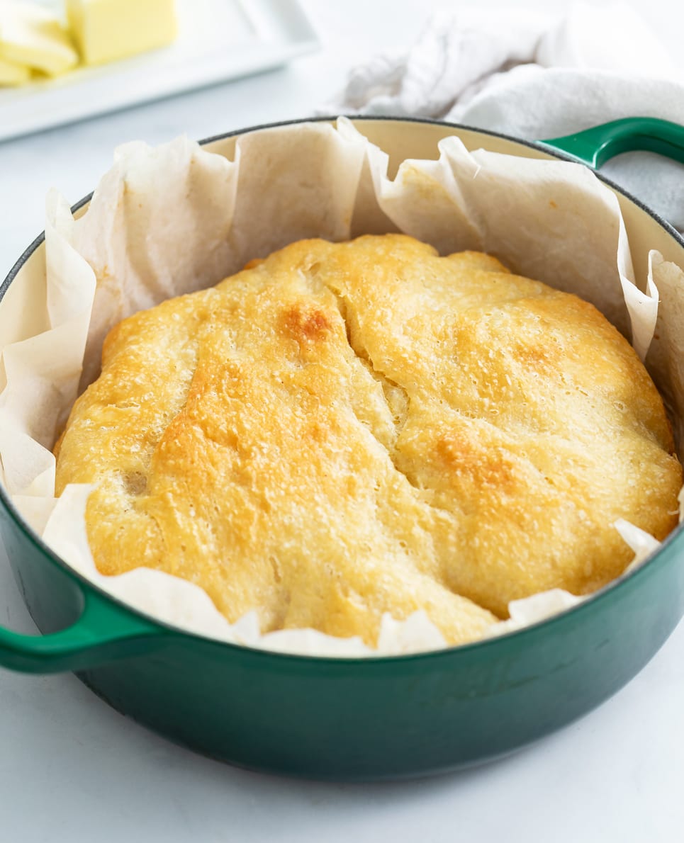 No Knead Bread in a Dutch oven with parchment paper around it.