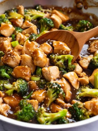 A wooden spoon scooping up Teriyaki Chicken in a skillet.
