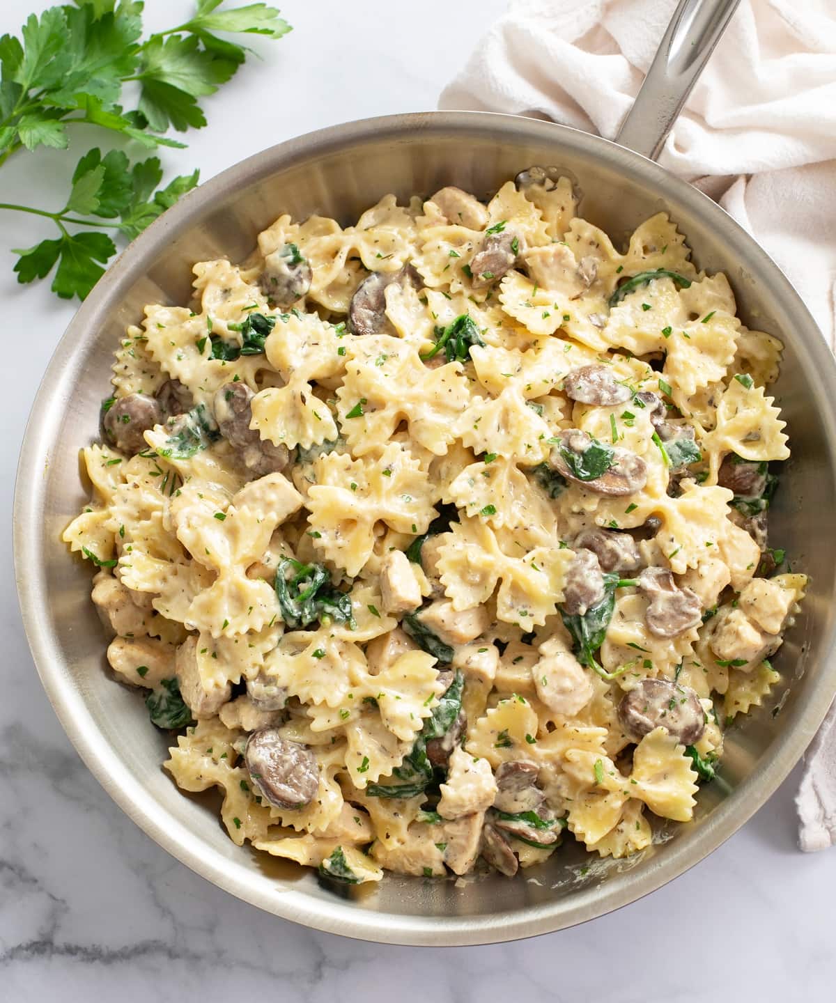 Mushroom Chicken Pasta in a skillet with spinach and a cream sauce.