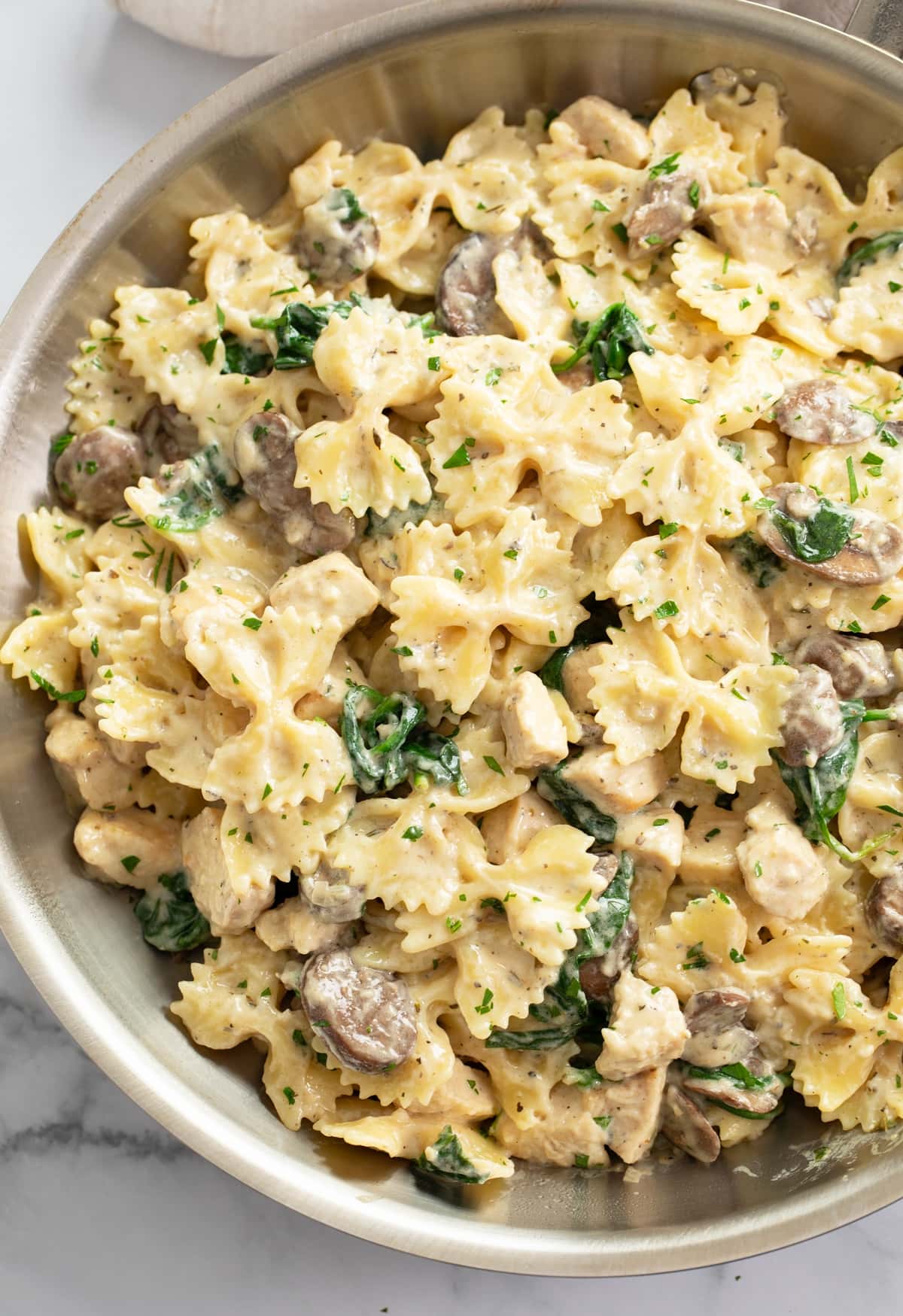 Mushroom Chicken Pasta in a skillet with creamy sauce and spinach.
