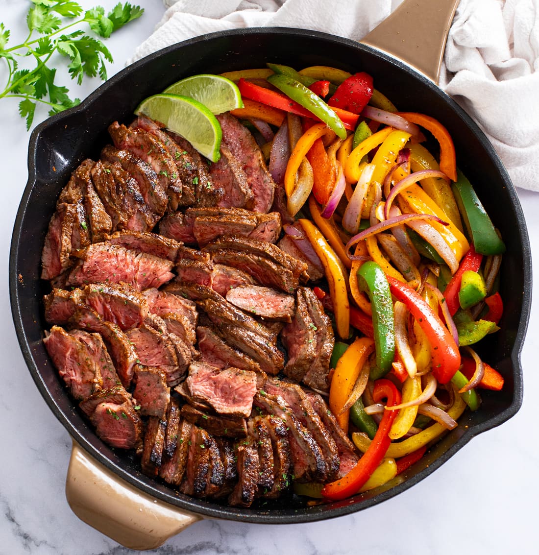 Steak Fajitas in a skillet with seasoned steak, onions, and peppers.