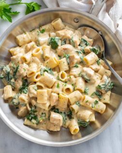 Chicken Spinach Pasta in a stainless steel skillet with a creamy white sauce.