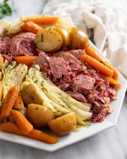 Corned Beef and Cabbage on a white platter with carrots and potatoes.