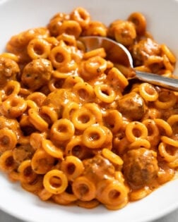 A white bowl filled with Homemade Spaghettios with a spoon in the back.