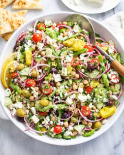 Overhead view of classic Greek Salad with vegetables, feta, chickpeas, and homemade dressing.
