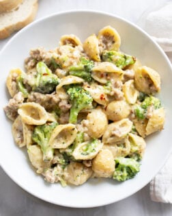 A white bowl with Sausage and Broccoli Pasta in a creamy sauce.